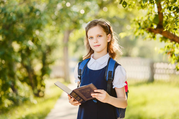 ten-year-old cute schoolgirl with a book in the outdoors - Fotó, kép