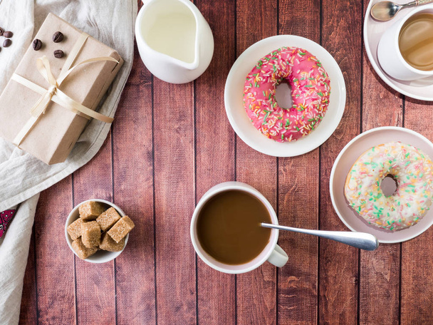 Donuts and coffee on wooden table. Top view with copy space. - 写真・画像