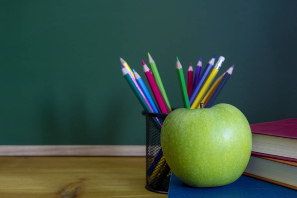 green apple resting on the book with chalk board as background - Photo, image