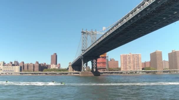 LOW ANGLE VIEW CLOSE UP: Happy couples and friends jet-skiing on East River under the iconic Manhattan Bridge along the busy highway on sunny summer day in New York City overlooking Downtown Manhattan - Footage, Video