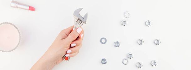 Creative long wide banner of woman hand pastel manicure polish holding spanner with copy space nuts and cosmetics isolated white background in minimalism style. Repair or improvement feminism concept - Foto, immagini