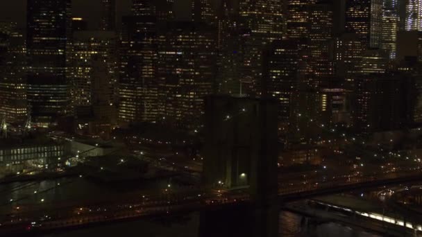 Zdjęcia lotnicze Heli, Close Up: Pływające powyżej zajęty interstate zacięty w kultowych Brooklyn Bridge oświetlone światłami, co prowadzi do dzielnicy biznesowej Downtown Manhattan. Dojazdy do pracy, podróży z pracy po zachodzie słońca - Materiał filmowy, wideo