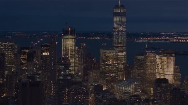 Hava Heli Shot, Close Up: ünlü landmarked gökdelenler Aşağı Manhattan iş bölgesinde güneş battıktan sonra ışıkları ile aydınlandı doğru uçan. Waterfront ofis binaları ve New York üst Körfezi - Video, Çekim