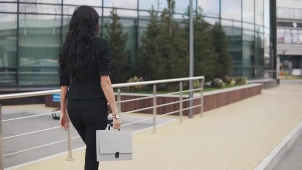 portrait of young confident business woman in suit with folder for papers in hands. a girl in a trouser suit walks down the street. - Filmmaterial, Video