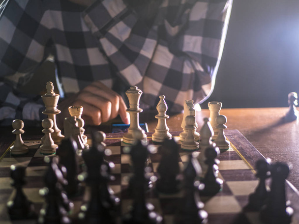 jonge bebaarde schaker spelen van een spel op een toernooi met donkere achtergrond - Foto, afbeelding