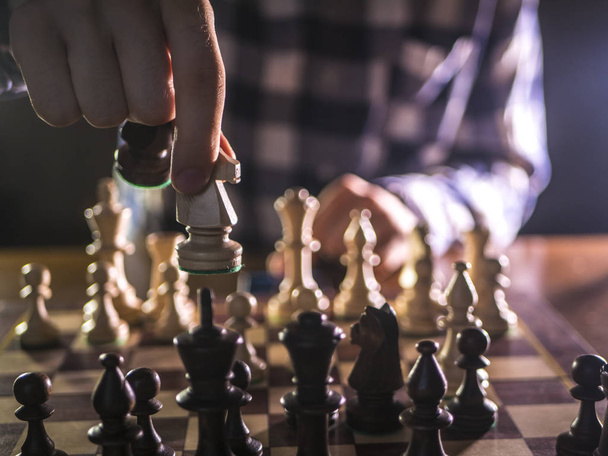 νεαρά αρσενικά grandmaster χέρι κάνοντας επόμενη κίνηση παίζει σκάκι σε σκοτεινό μέρος σε ένα τουρνουά - Φωτογραφία, εικόνα
