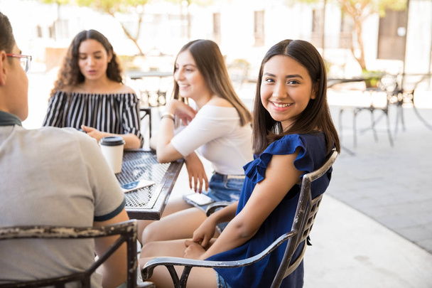 Retrato de una hermosa adolescente sentada con amigos en el café al aire libre sho
 - Foto, Imagen