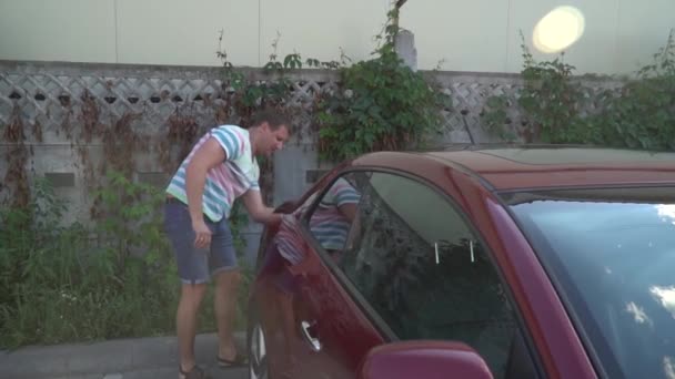junger kaukasischer Mann wäscht sein Auto auf der Selbstbedienungswaschanlage. Autowäsche. - Filmmaterial, Video