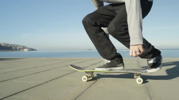 Zpomalený pohyb, Close Up, Dof: K nepoznání skateboardista skateboardingu a skákání 360 flip trik na promenádě podél oceánu v slunné léto. Skateboardista koni skateboard skákání kickflip trik - Záběry, video