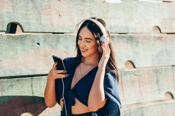 mooi meisje luisteren muziek met haar koptelefoon in de straat - Foto, afbeelding
