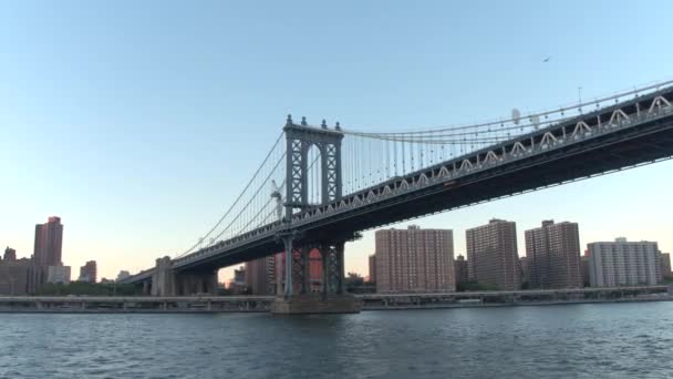 Lage hoekmening, Close Up: Sightseeing cruise op de East River langs beroemde New York City skyline. Wolkenkrabbers, kantoorgebouwen en luxe waterfront appartementen langs de iconische Manhattan Bridge bij zonsopgang - Video