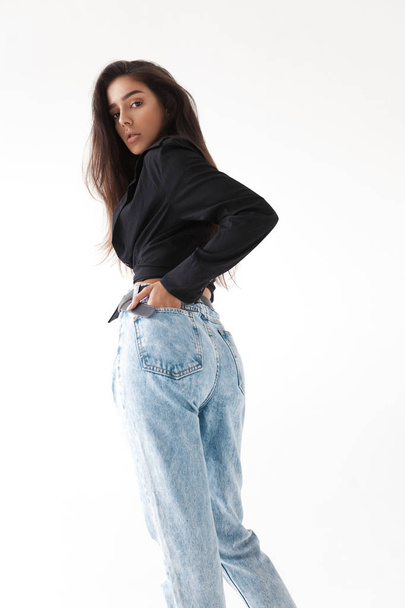 Young cool hipster girl in black shirt and blue banana jeans on white background. Fashionable modern style - Foto, imagen