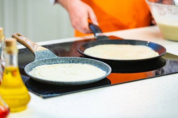 Küchenzubereitung: Der Koch brät frische Pfannkuchen in zwei Pfannen - Foto, Bild