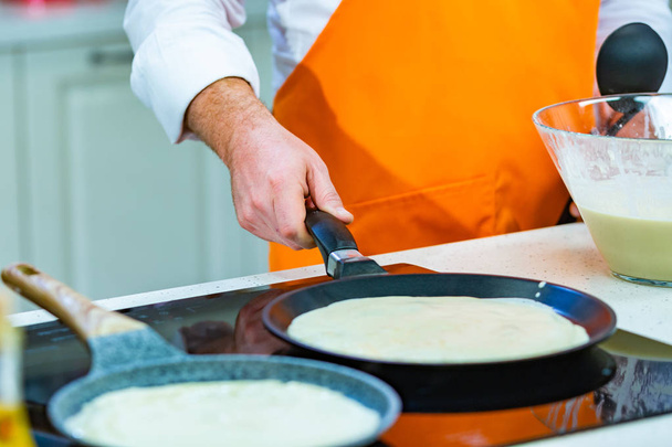 Cucina Preparazione: lo chef frigge frittelle fresche in due padelle
 - Foto, immagini