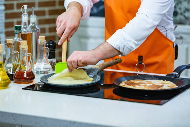 Кухня Подготовка: шеф-повар жарит свежие блины в двух кастрюлях
 - Фото, изображение