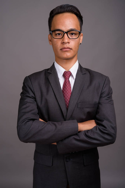 Young handsome Indian businessman against gray background - Photo, Image