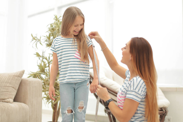 attentive mother and daughter make measurements for new clothes - Photo, image