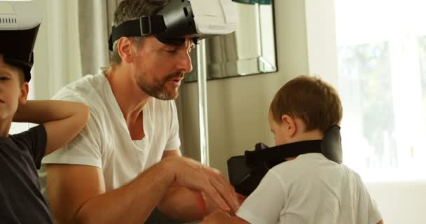 Father and kids using virtual reality headsets on sofa at home 4k - Кадри, відео