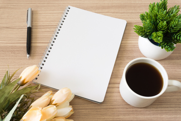 コーヒー カップ、鉢植えの植物と木の机の上の花のノート。テキスト コピー スペース. - 写真・画像