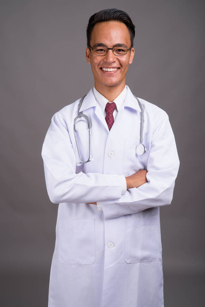 Jonge knappe man van de Indiase arts tegen de grijze achtergrond - Foto, afbeelding
