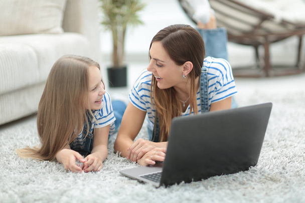 Mutter und ihre kleine Tochter benutzen in ihrer Freizeit einen Laptop - Foto, Bild