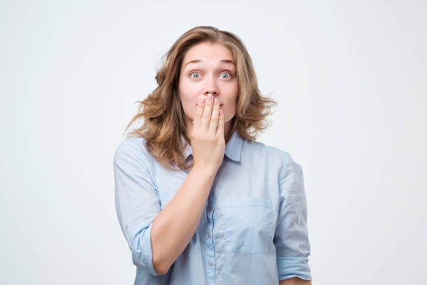 Young caucasian woman closing her mouth and wide open eye isolated on white background. She is surprised by unexpected pleasant news. I can not keep it a secret - Photo, Image