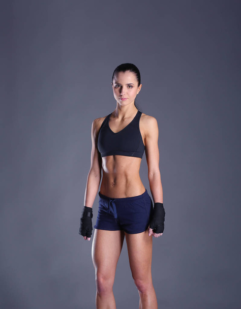 Muscular young woman posing in sportswear against black background - Photo, image