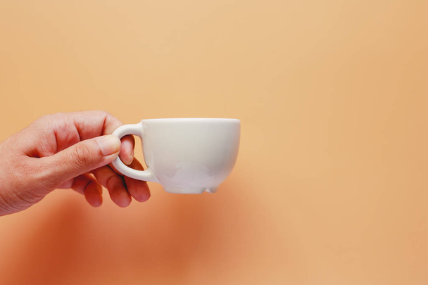 Χέρι που κρατά το φλιτζάνι του καφέ σε μπεζ χρώμα φόντου για ποτά και ποτά έννοια - Φωτογραφία, εικόνα
