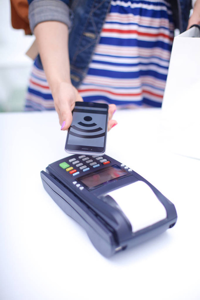 Customer is paying with smartphone in shop using NFC technology. NFC technology. Customer is paying - 写真・画像