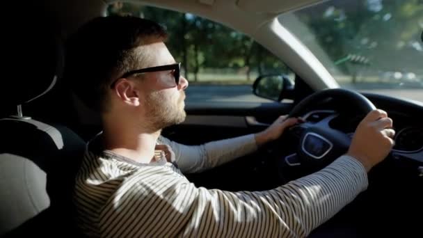 Egy ember egy modern autó vezetés. Egy jóképű férfi, az a nap, védő szemüveg, szakáll magabiztosan irányítja. - Felvétel, videó