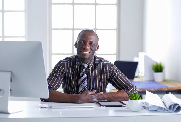 Handsome afro american businessman in classic suit is using a laptop and smiling while working in office - Fotoğraf, Görsel