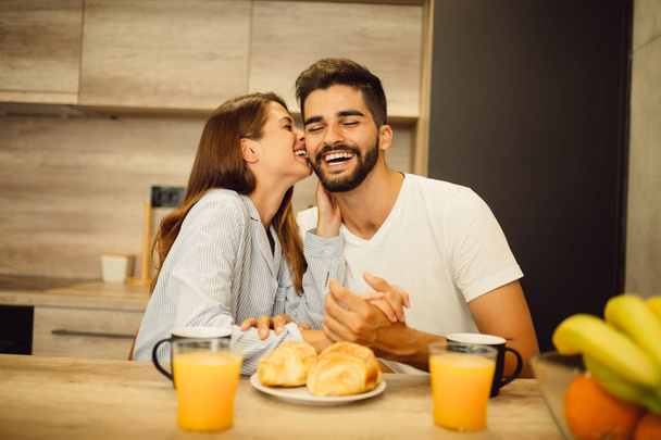 Young good looking couple is having fun while they are having breakfast and coffee in the morning - Фото, изображение