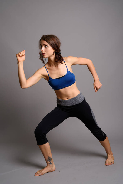 Young beautiful woman ready for gym against gray background - Фото, зображення