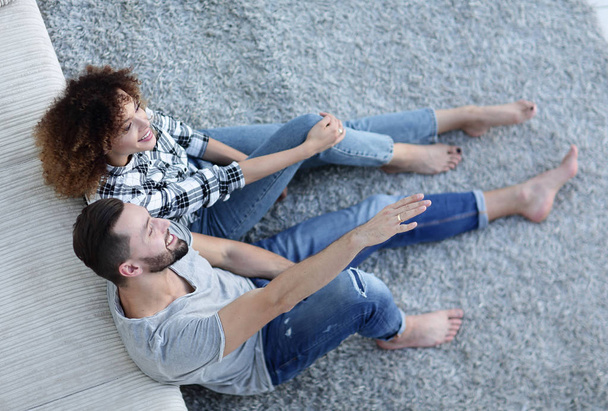 newlywed couple sitting on a carpet in a new living room - Photo, Image