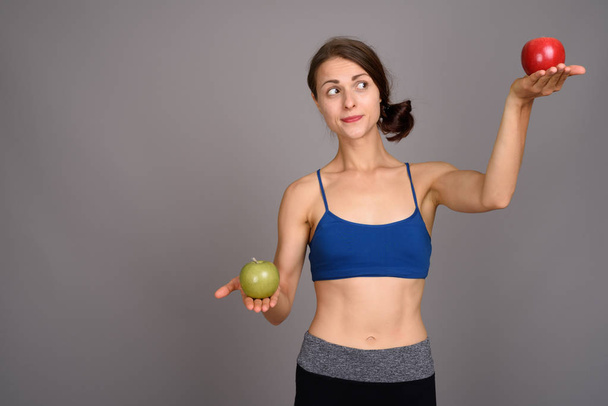 Young beautiful woman ready for gym against gray background - Foto, Imagen