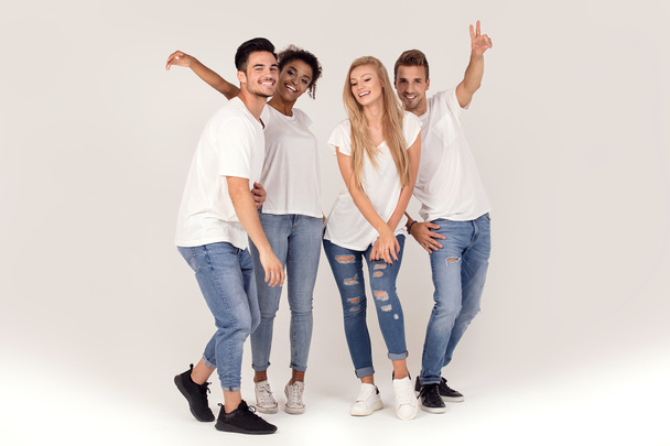 Groupe de jeunes gens attirants multi-ethniques portant des chemises blanches, souriant et s'amusant ensemble, posant en studio
. - Photo, image