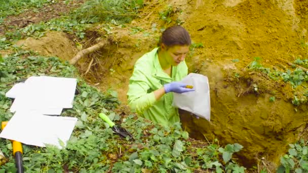 Женщина-эколог берёт образцы почвы и кладёт их в бумажный конверт.
 - Кадры, видео