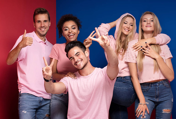 Grupo de jóvenes multiétnicos atractivos sonriendo y divirtiéndose juntos, posando sobre un fondo colorido
. - Foto, Imagen
