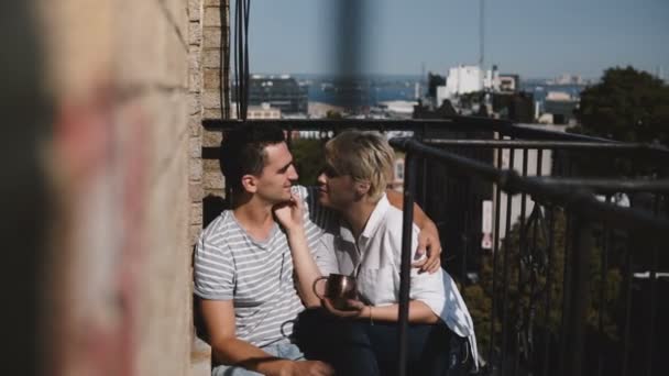 Piękna para romantyczny wieloetnicznym boso siedzi blisko siebie, rozmowa, całując delikatnie w piękny słoneczny balkon. - Materiał filmowy, wideo