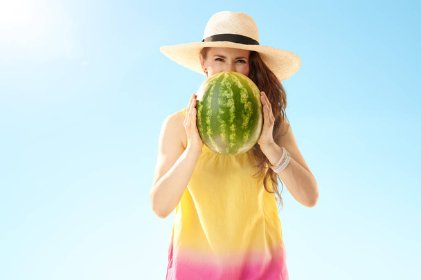happy healthy woman in straw hat looking out from watermelon against blue sky - Fotografie, Obrázek