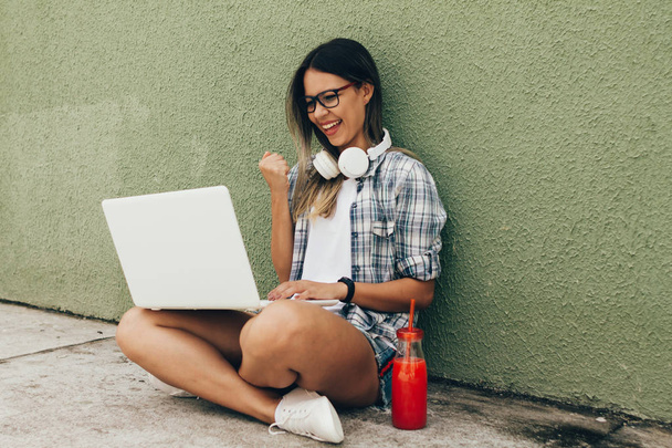 Portrait of young woman using laptop with headphones on the street - Fotoğraf, Görsel