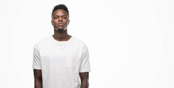 Young african american man wearing white t-shirt with serious expression on face. Simple and natural looking at the camera. - Foto, afbeelding