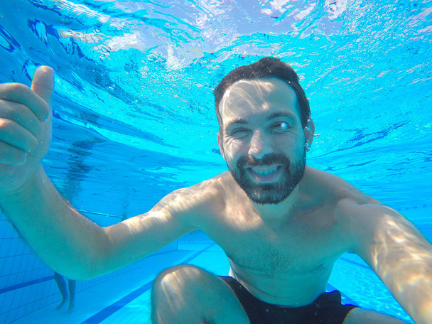 Underwater portrait of smiling man. Person having fun in swimming pool. Summer vacation concept - Foto, Imagen