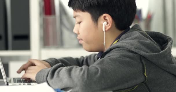 Cute asian teen boy doing your homework with laptop computer at home. - Footage, Video