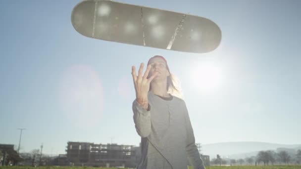 Αργή κίνηση, Close Up, Dof: Cool χαρούμενος skateboarder έχοντας διασκέδαση παίζοντας με skateboard του, ρίχνοντας επάνω στον αέρα και πιέζοντάς την κάμερα πέρα από τον ήλιο. Ευτυχισμένος σκέιτερ παίζει με skateboard - Πλάνα, βίντεο