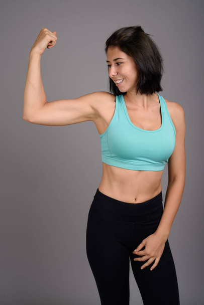 Young beautiful woman ready for gym against gray background - Fotoğraf, Görsel
