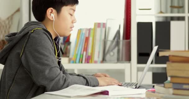 Χαριτωμένο ασιατικό έφηβος αγόρι κάνει την εργασία σας με το φορητό υπολογιστή στο σπίτι. - Πλάνα, βίντεο