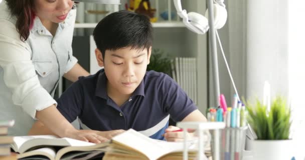 Ładna Azjatka Matka pomaga Twój syn robi swoją pracę domową w domu z twarzy uśmiech razem. - Materiał filmowy, wideo