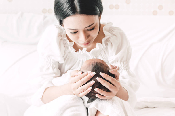 Mãe segurando bebê em seus braços em um quarto branco.Amor do conceito de família
 - Foto, Imagem