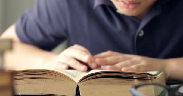 Zbliżenie dłoni azjatycki chłopiec czytanie książki . - Materiał filmowy, wideo